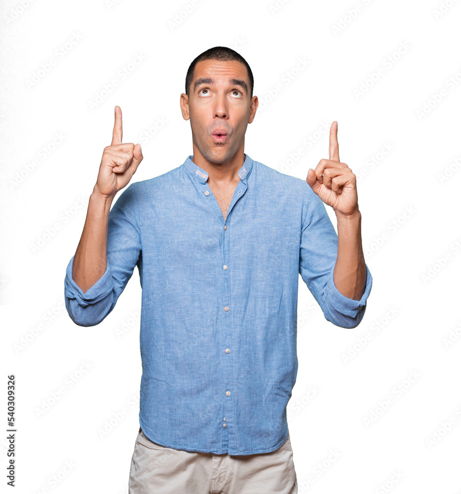 Amazed young man pointing up with his finger Amazed young man pointing up with his finger