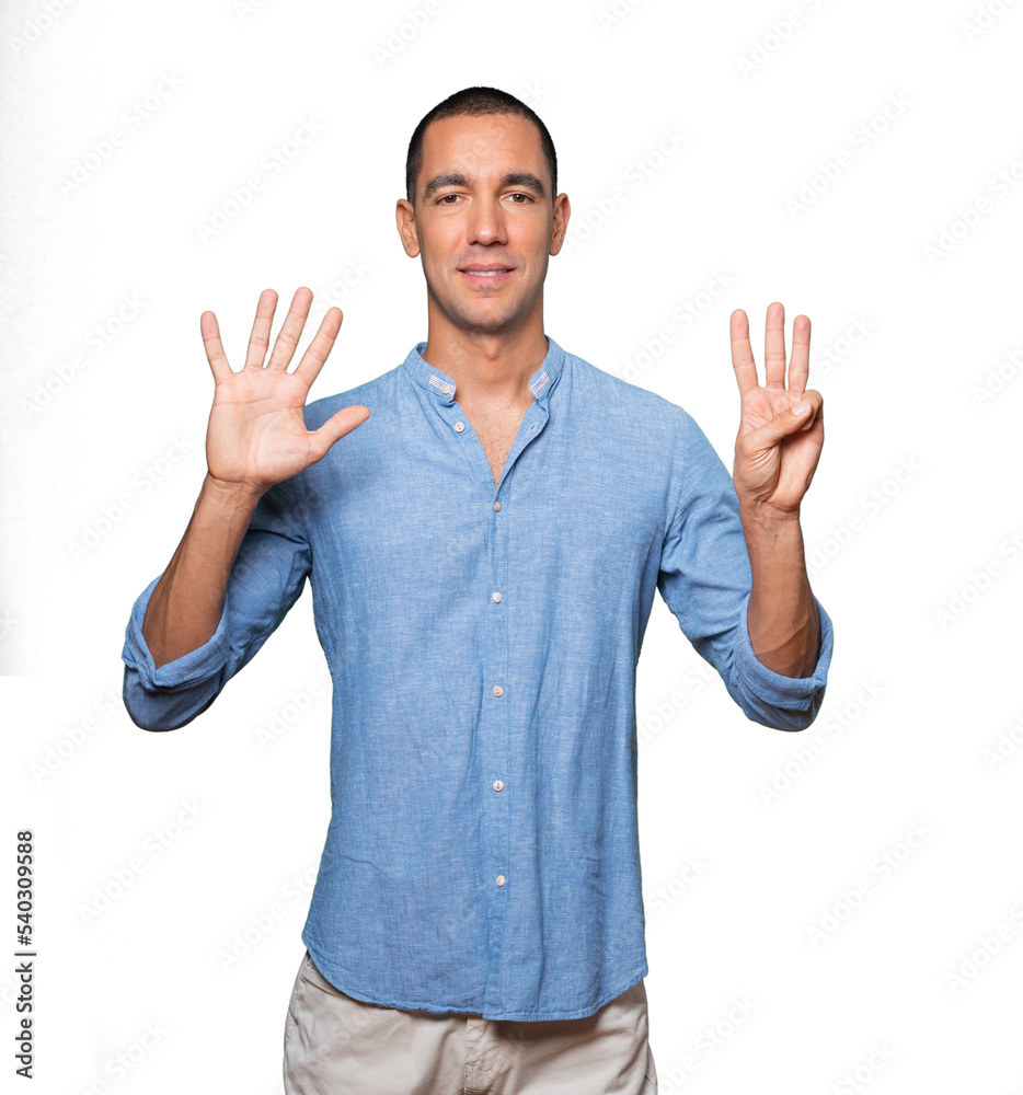 Happy young man doing a number eight gesture with his hands Happy young man doing a number eight gesture with his hands
