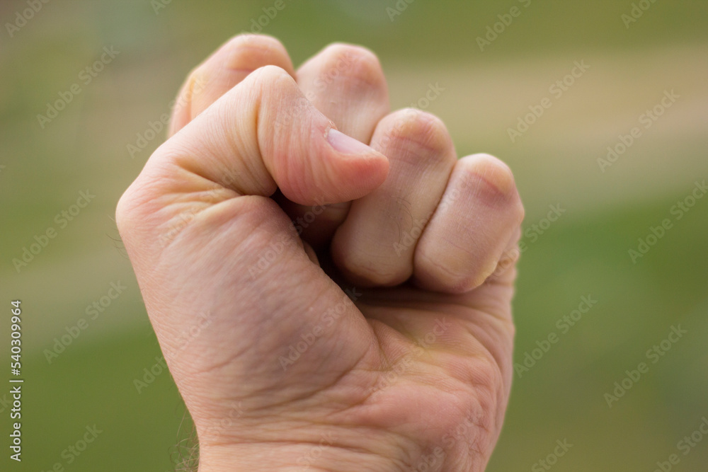 Hand clenching a fist on a green background close-up Hand clenching a fist on a green background close-up