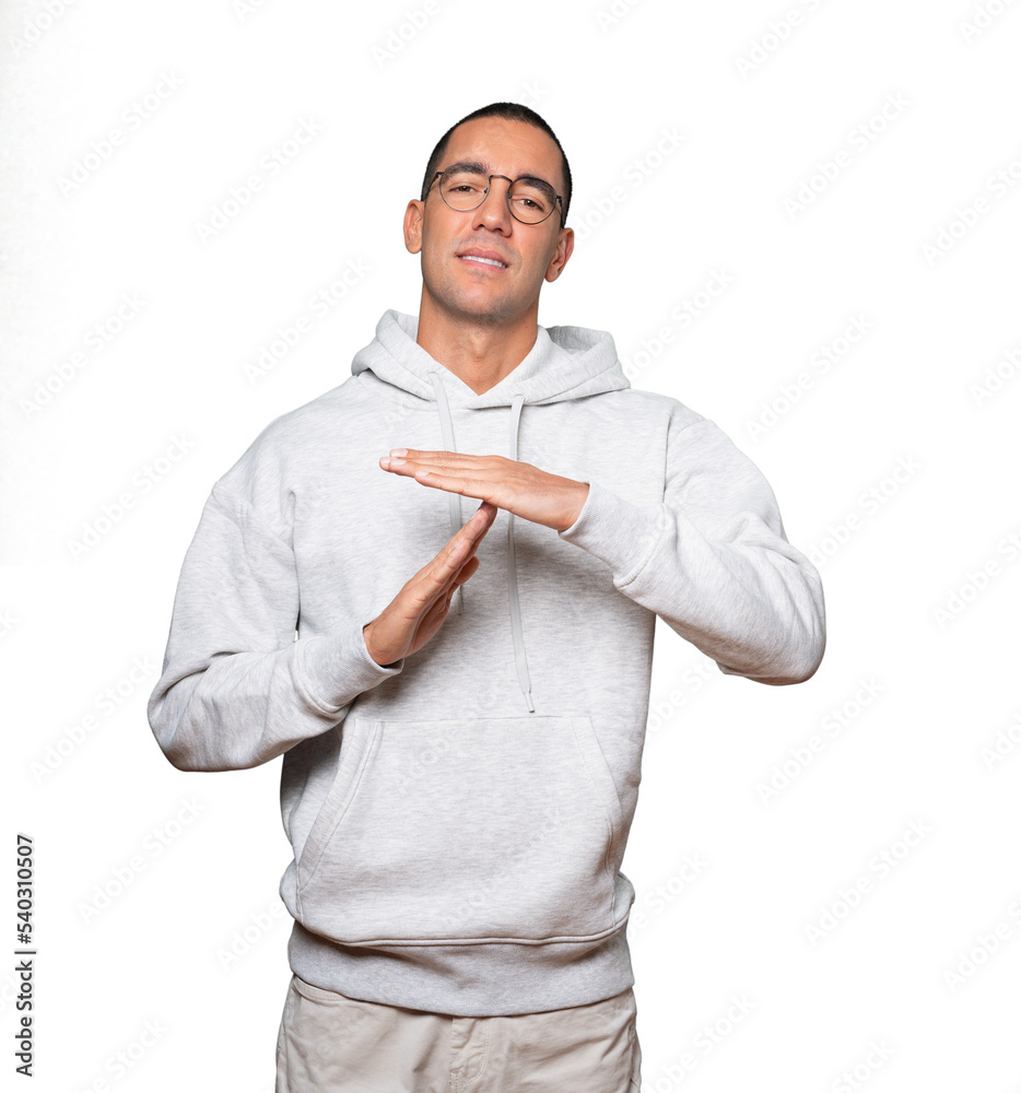 Stressed young man making a time out gesture with his hands