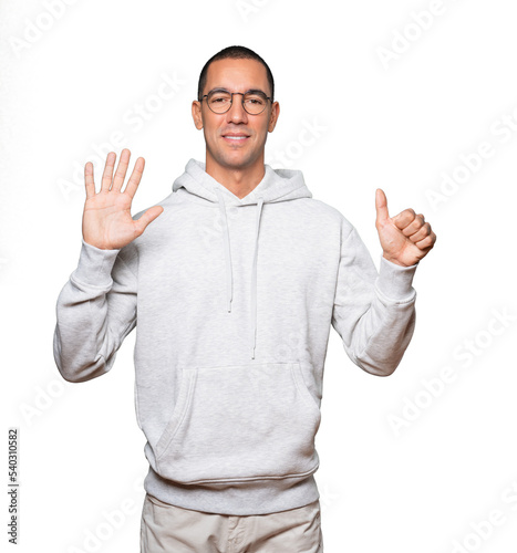 Happy young man doing a number six gesture with his hands