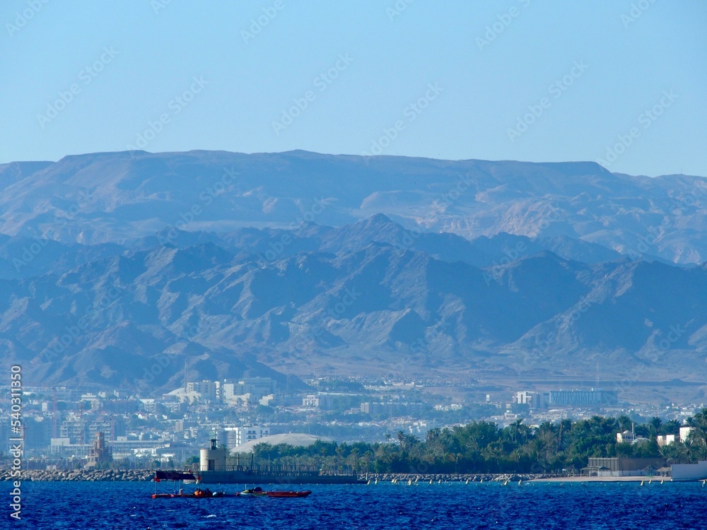 A landscape shot overlooking the Red Sea from Aqaba, Jordan, with a city and mountain range in view