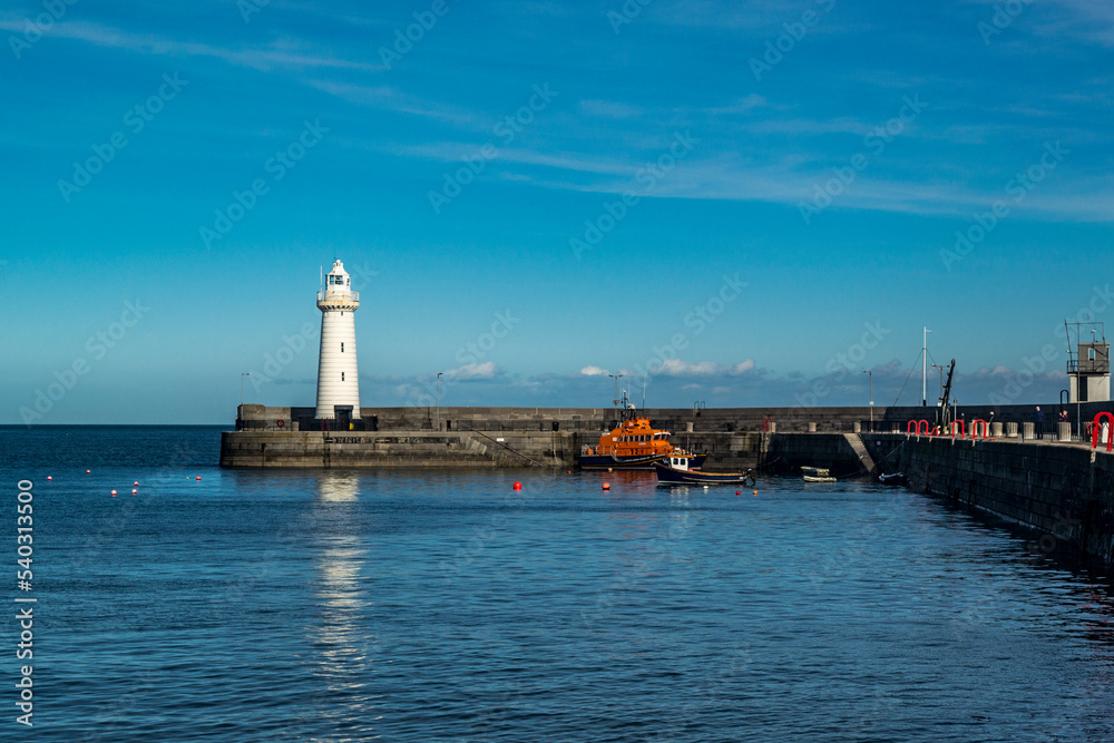 Donaghadee, County Down, Northern Ireland - March 09 2018. Donaghadee Harbour with its lighthouse at the mouth with a lifeboat and fishing boat moored up.