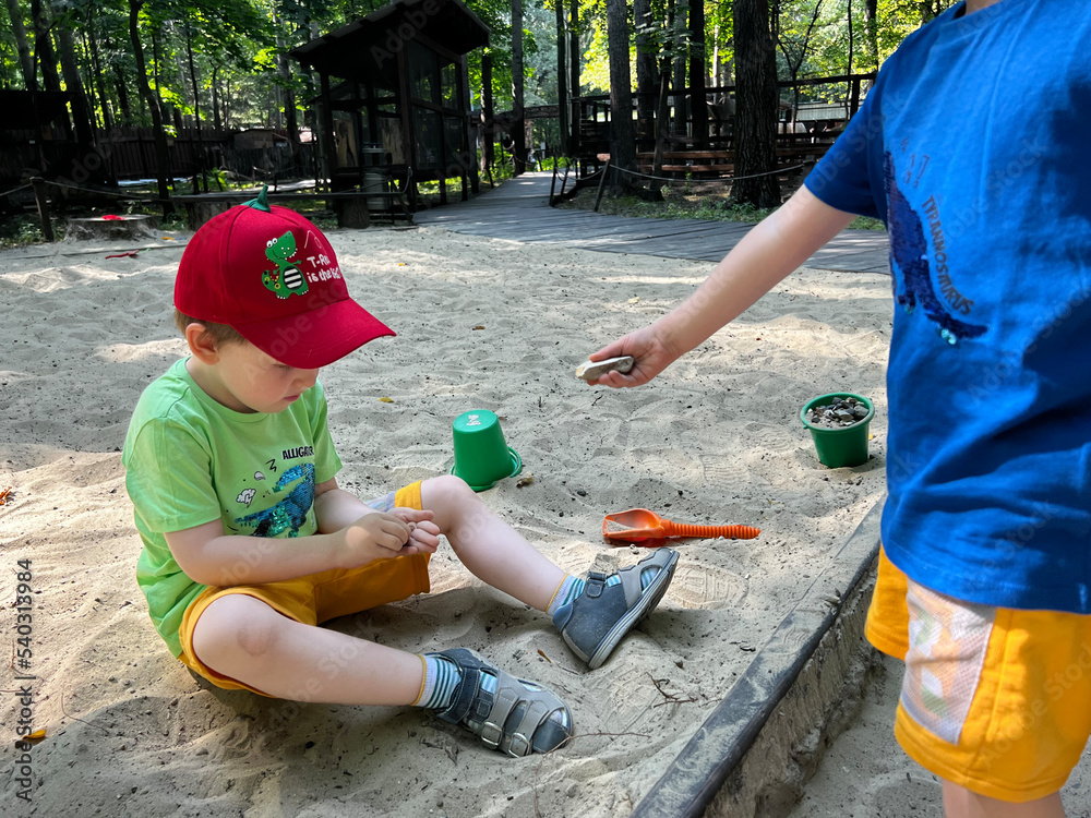 Two little boys play in the sandbox, children play in the sand