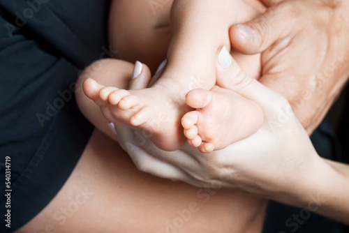 Baby feet in parents hands. Tiny Newborn Baby's feet on parents shaped hands closeup. Parents and they Child. Happy Family concept.
