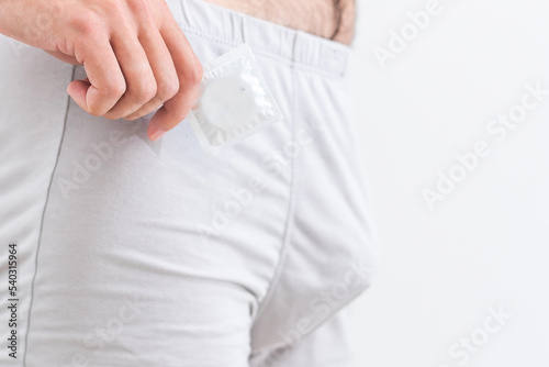 a man in underwear holds a condom.