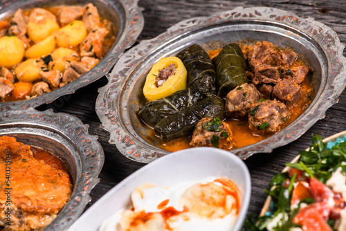 Eid Mubarak Traditional Ramadan Iftar dinner. Assorted tasty food in authentic rustic dishes on wooden blue background. Turkish Bosnian food meat kebab, pita, Sarma, klepe, sogan dolma.