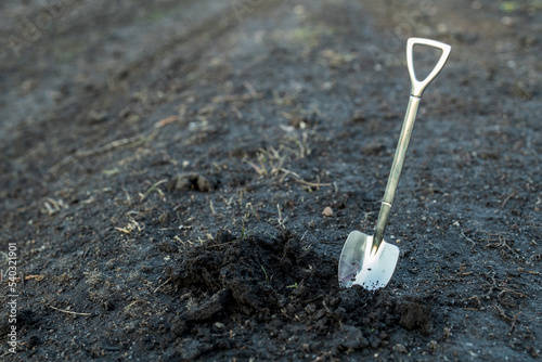 a shovel is inserted into the soil, next to it is loose excavated earth photo