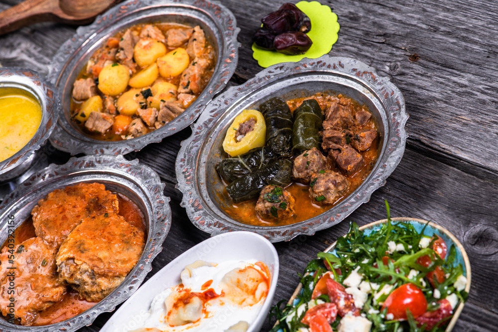 Eid Mubarak Traditional Ramadan Iftar dinner. Assorted tasty food in authentic rustic dishes on wooden blue background. Turkish Bosnian food meat kebab, pita, Sarma, klepe, sogan dolma.