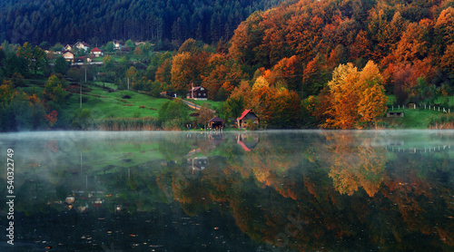 Fall colours and cottage reflected in the still waters of Lake.Autumn nature. Vivid morning in colorful park © Amir Bajric