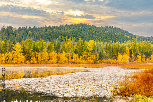 peaceful autumn scene of Blanchard Lake in northwest Montana with colorful fall foliage and sunset sky in background photo