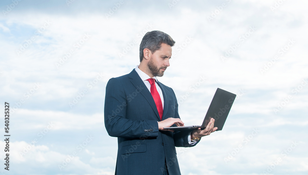 boss in suit using laptop on sky background boss in suit using laptop on sky background