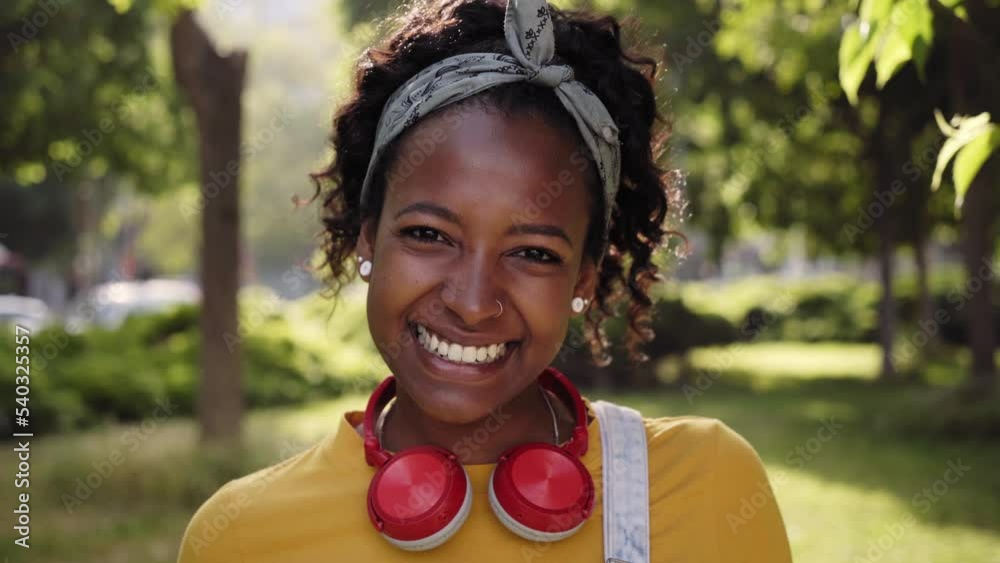 Portrait of a Smiling pretty woman happy looking at camera rejoicing smiling white teeth, outdoor close-up. Student girl with headphones with a positive attitude. 