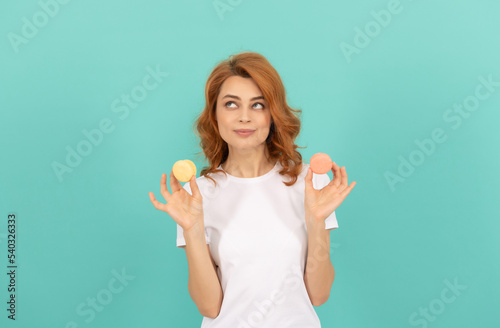 positive girl hold sweet macaron french cookie on blue background