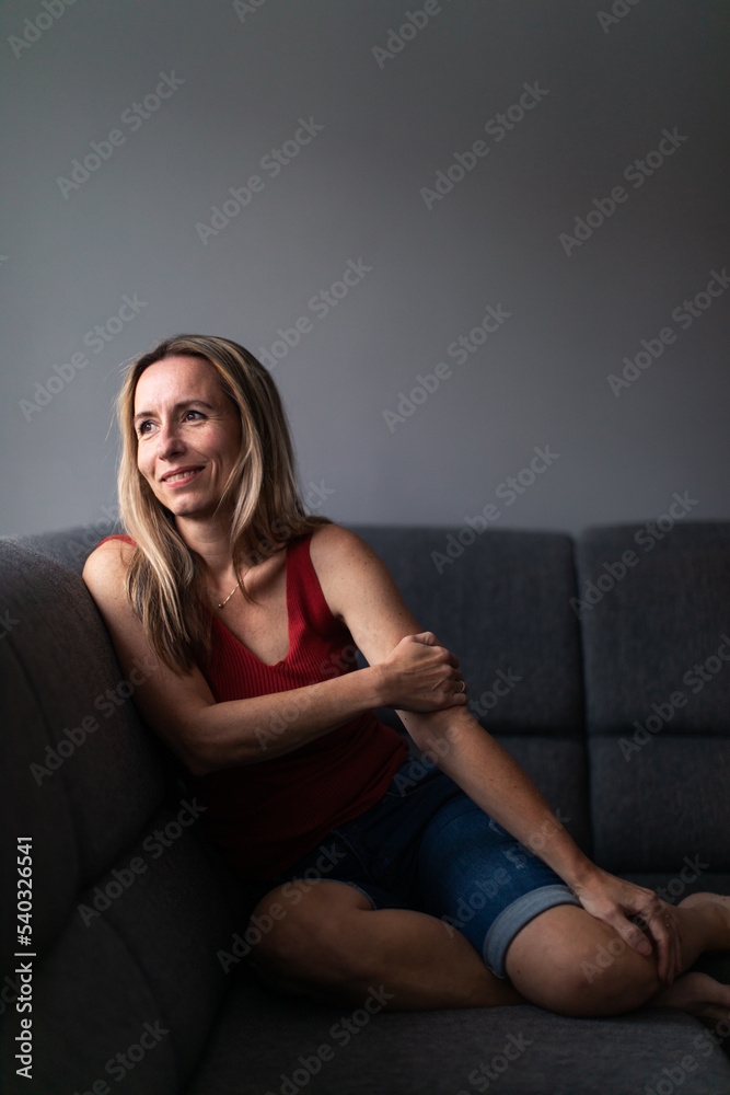 Mid-aged woman at home relaxing on a sofa (color toned image) Mid-aged woman at home relaxing on a sofa (color toned image)