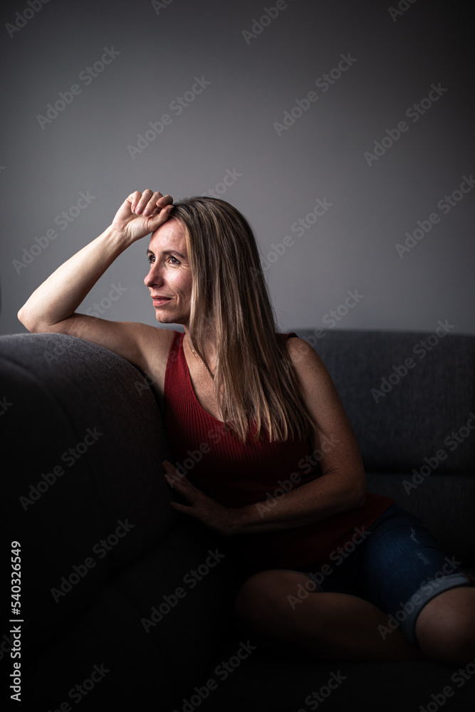 Mid-aged woman at home relaxing on a sofa (color toned image)