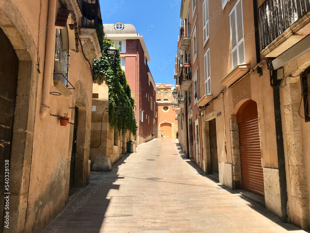 Tarragona, Spain, June 2019 - A narrow city street with buildings on the side of a building