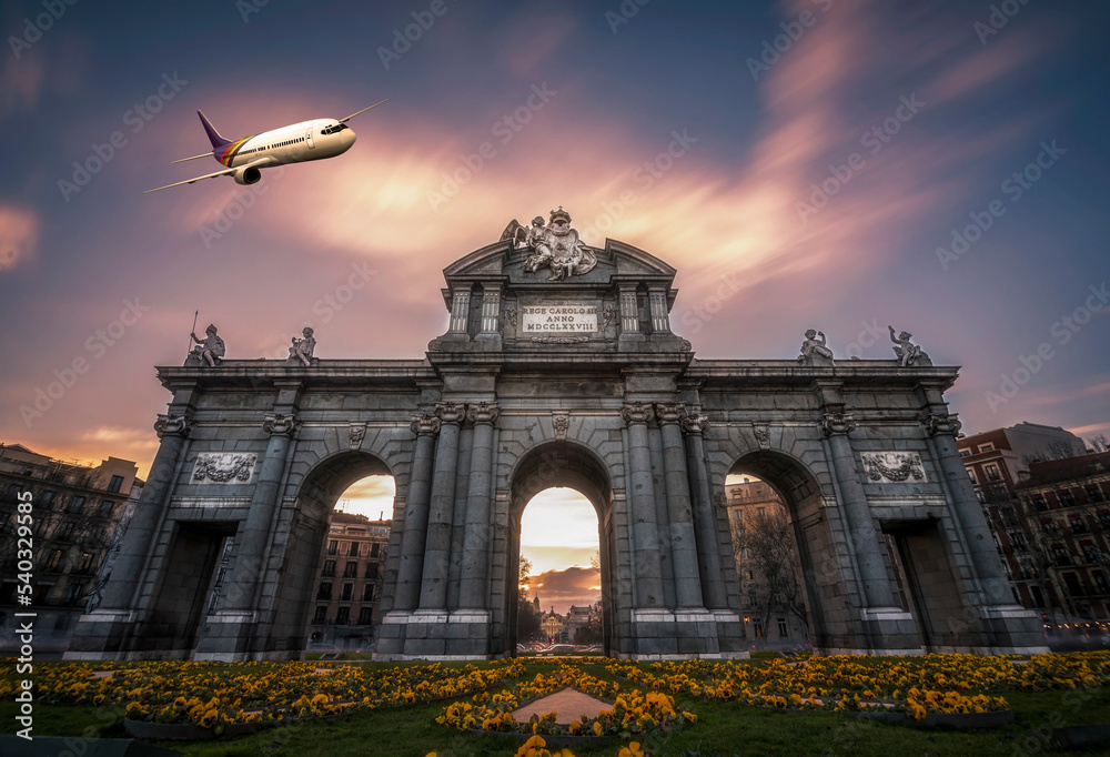 Obraz premium Alcala Gate of Madrid with sunset clouds on sky and an airplane