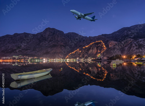 Heart shaped Kotor castle with evening lights and an airplane on sky