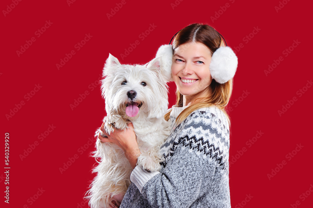 Woman in fluffy white headphones with her white dog Woman in fluffy white headphones with her white dog