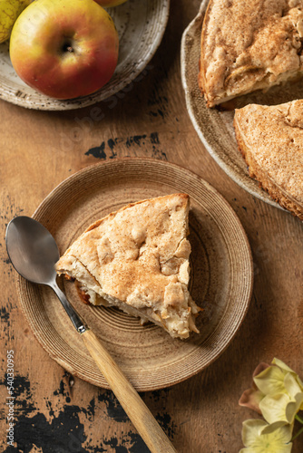 Piece of apple pie charlotte with apples and flowers on wooden background, top view, flat lay