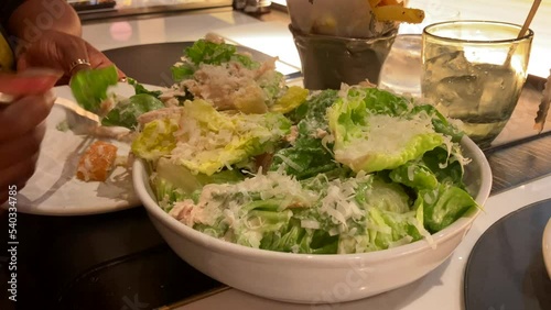 Close Up of African American Woman Plating Up Caesar Salad At A Restaurant photo