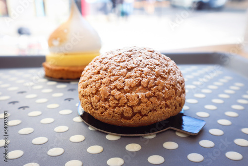 Close up of French cream puff crack bun (Choux au Craquelin) in a plate with bright background, a dessert base of savory little choux dough bun filled with sweet variety cream. photo