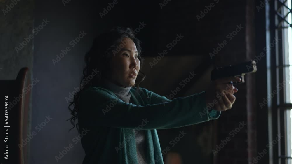 4k Young woman holds gun and aims, stands in room spbd. Close view