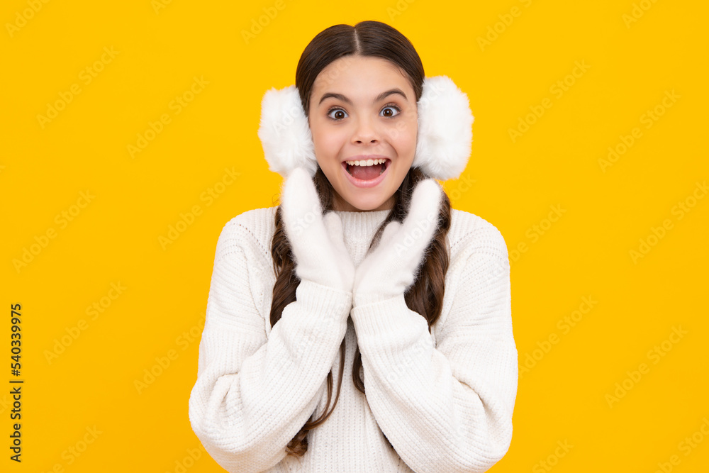 Teenage girl with winter warm earmuff ear-flaps over isolated yellow background. Winter christmas holidays, new year mood. Kids warm clothes. Excited teenager girl. Teenage girl with winter warm earmuff ear-flaps over isolated yellow background. Winter christmas holidays, new year mood. Kids warm clothes. Excited teenager girl.