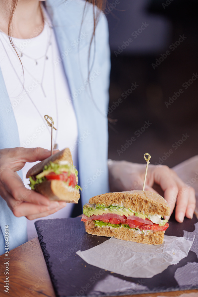 girl eating delicious sandwich close up in modern cafe