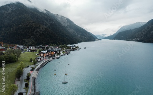 Aerial of the Achen lake's coastline with boats in Achensee region surrounded by green mountains