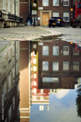 Blurred image of London street and buildings in reflection of puddle of water