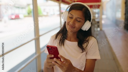 Young beautiful hispanic woman listening to music and dancing at street