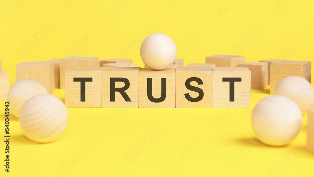 word trust written with wooden dices on yellow background. word trust written with wooden dices on yellow background.