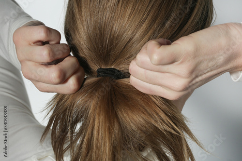 Serie of photos of making a low ponytail with basic elastic hair band. Back view of young woman tied her hair in ponytail. photo