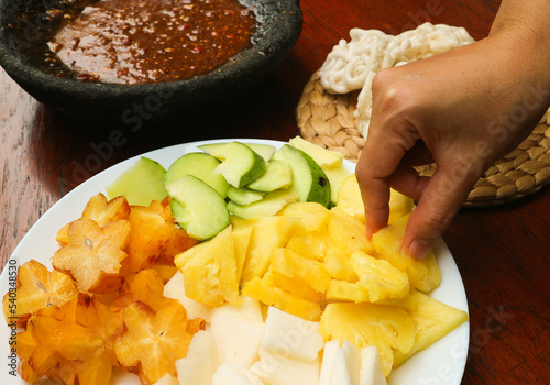 Hand pick pineapple of Lotis buah or rujak. fruits with hot chili paste and chips or kerupuk. indonesian traditional fruit salad photo