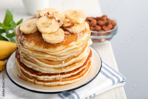Tasty pancakes with sliced banana served on white wooden table. Space for text