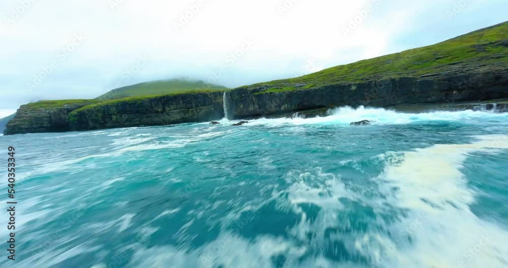 Aerial Panning Scenic Shot Of Waterfall On Island, Drone Flying Forward Over Wavy Ocean - Faroe Islands, Denmark Aerial Panning Scenic Shot Of Waterfall On Island, Drone Flying Forward Over Wavy Ocean - Faroe Islands, Denmark