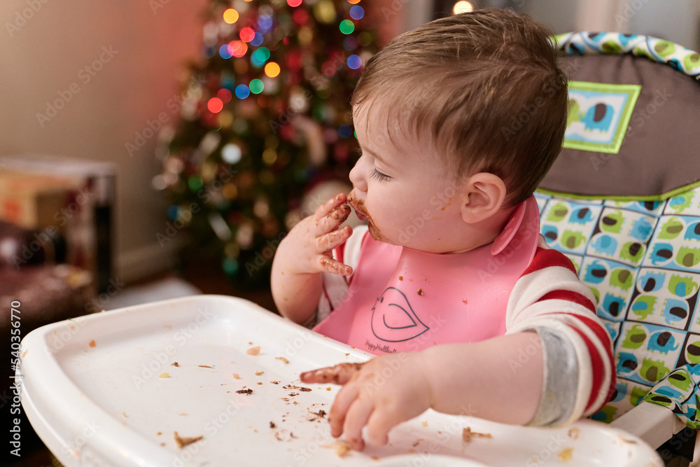 cute toddler eating chocolate candy in his high chair cute toddler eating chocolate candy in his high chair