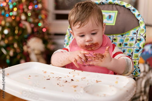 cute toddler eating chocolate candy in his high chair