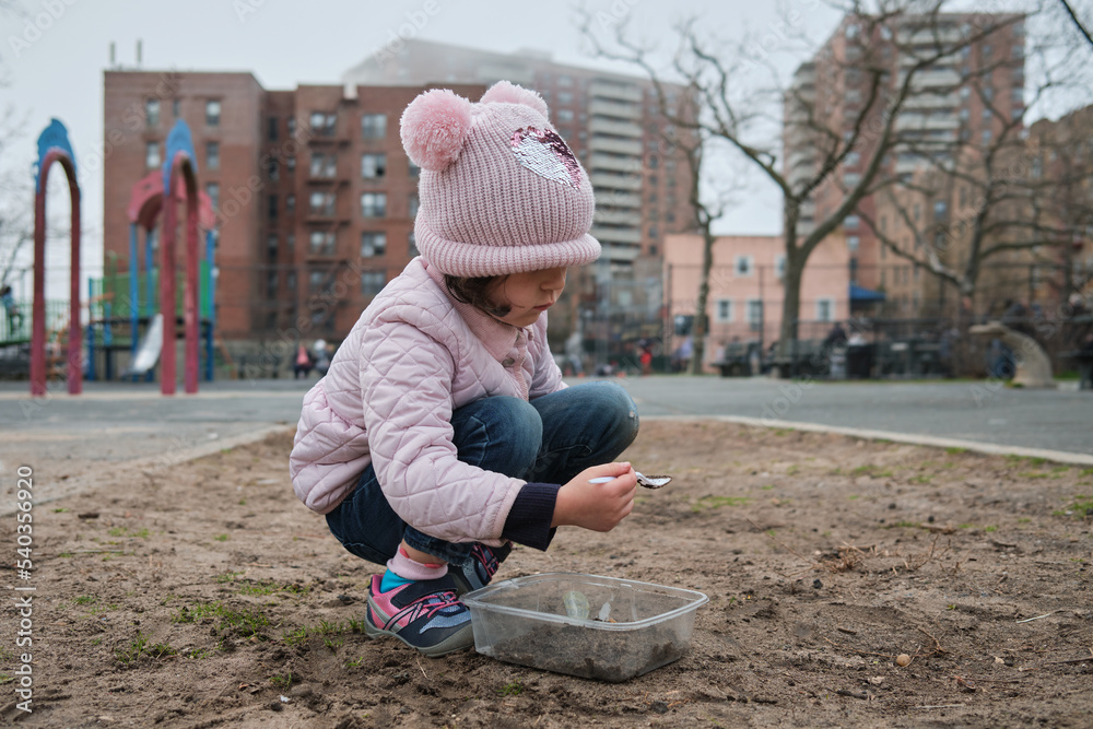 Girl digging in the dirt on the playground on a foggy fall day Girl digging in the dirt on the playground on a foggy fall day