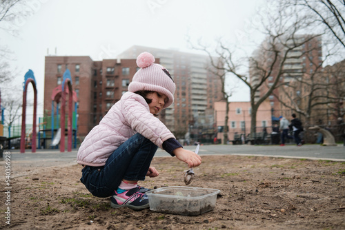 Girl digging in the dirt on the playground on a foggy fall day © Klarion