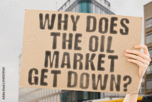 The question " Why does the oil market get down? " is on a banner in men's hands with blurred background. Depressed. Drop. Fossil. Fuel. Oil. Petroleum. Petrol. Rating. Crude. Energy. Market