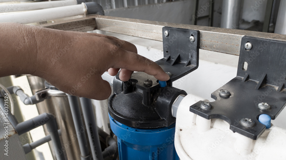 Obraz premium The man pressing the pressure relaease button for replace the case water filter.