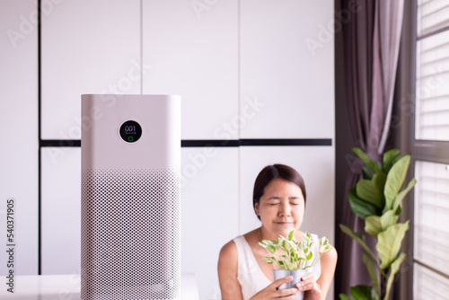 Air purifier white colour modern style in a living room for refresh air flow with blur happy woman at home,Advanced air purifying and protect Pm2.5