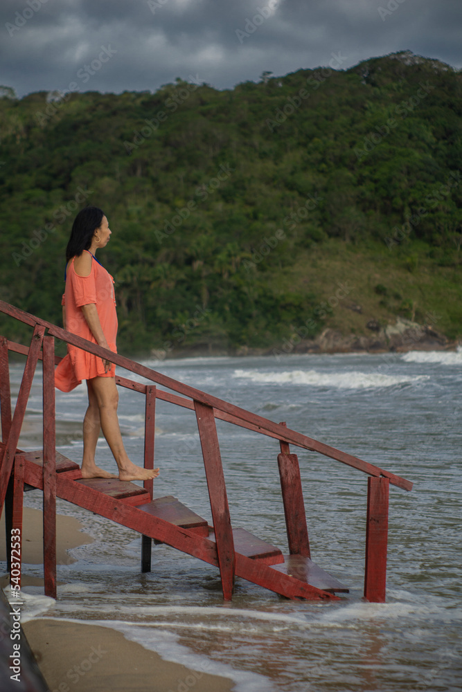 elderly woman enjoying trip, blue sky in the background, on a beach on the stairs elderly woman enjoying trip, blue sky in the background, on a beach on the stairs