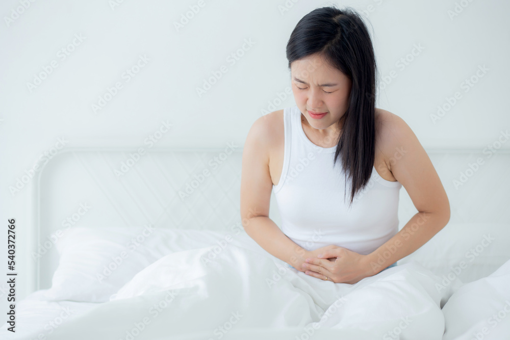 Young asian woman sitting on bed pain stomach or bowel with disease constipation in the bedroom at home, unhappy female sick and menstruation and stomachache, medical and health concept. Young asian woman sitting on bed pain stomach or bowel with disease constipation in the bedroom at home, unhappy female sick and menstruation and stomachache, medical and health concept.