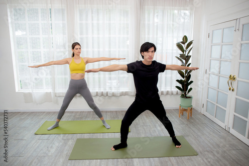 Young woman and man doing yoga with stretch muscles leg and hands at home, couple training practicing workout with yoga for bodycare, rehab with flexible of body, sport and health concept.