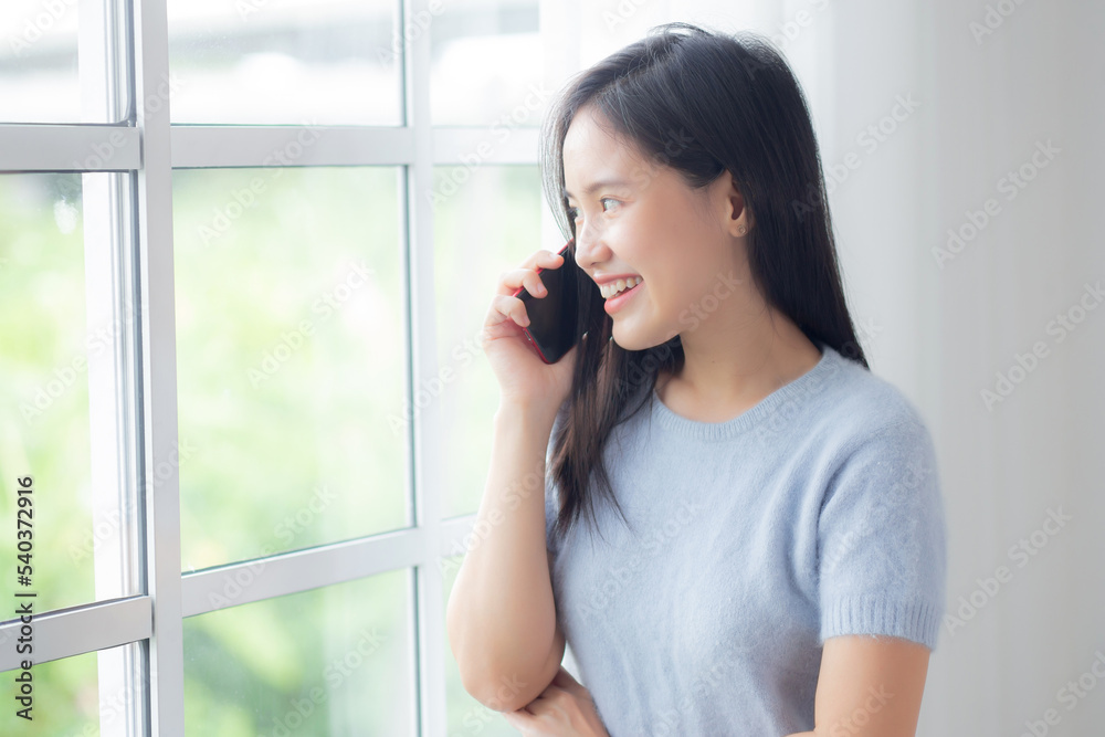 Happiness young asian woman talking with smartphone in the living room at home, female smiling and speaking with smart phone while relax and cozy at home, lifestyles and communication concept. Happiness young asian woman talking with smartphone in the living room at home, female smiling and speaking with smart phone while relax and cozy at home, lifestyles and communication concept.
