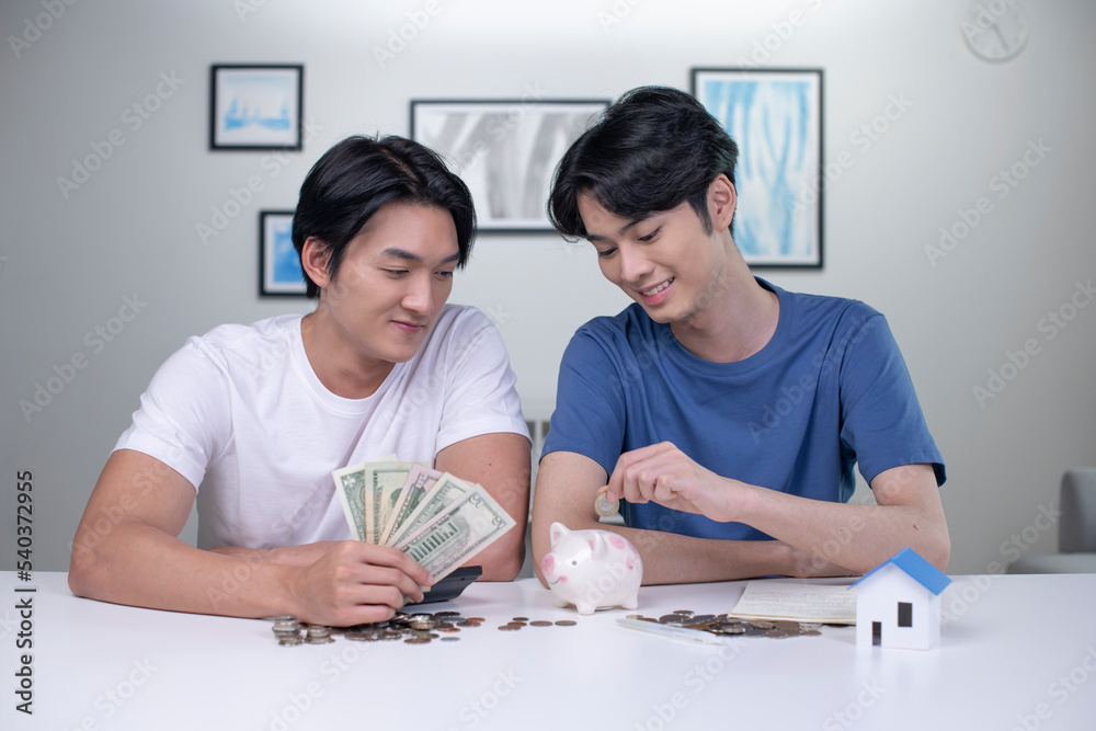 Young happy Asian gay couple saving money to buy a house. LGBT men couple saving money for family and home. Young happy Asian gay couple saving money to buy a house. LGBT men couple saving money for family and home.
